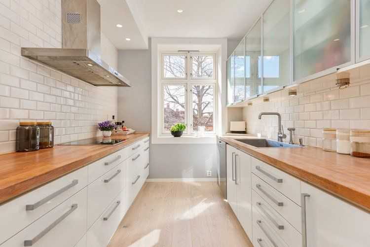 cuisine blanche en deux lignes équipée de deux plans de travail en bois massif et crédence en carrelage métro blanc